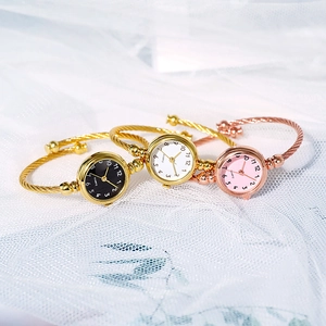 Detailed shot of open bangle quartz watches in gold and rose gold on white tulle