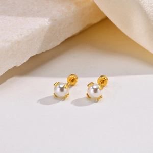 Detailed close-up of gold-plated stainless steel pearl stud earrings on satin