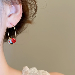 Close-up of model wearing resin colorful bead hoop earrings with vibrant dot patterns