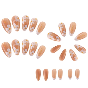 Detail view of nude press-on nails featuring white daisy patterns and gold glitter accents