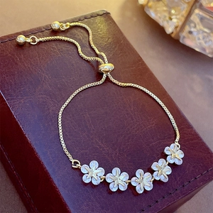 Elegant gold-plated flower bracelet with star-centered zircon crystals on a leather box