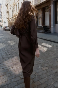Détail d'une robe midi en satin marron foncé montrant le tissu fluide dans une rue chic