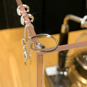 Elegant silver snake ring with sparkling crystals and green gem eyes on display stand