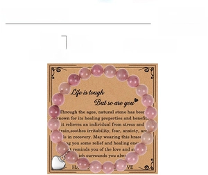 Détail du bracelet en perles de rhodochrosite rouge avec breloque cœur sur carte