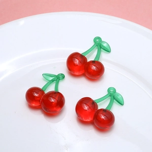 Detailed close-up of cherry resin charms in a white dish for DIY jewelry making