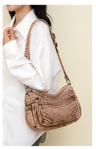 Detail of a brown textured crossbody bag with multiple zip pockets and adjustable strap