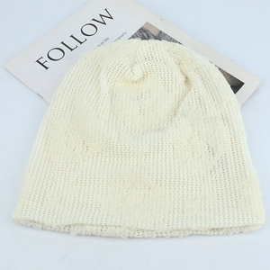 Detail of cream lace crochet beanie with intricate floral cutout patterns and mesh texture