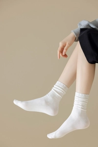 Gros plan de chaussettes mi-mollet en coton blanc à côtes verticales de profil arrière