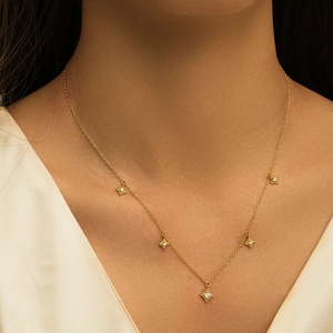 Close-up of a gold S925 sterling silver necklace with five sparkling star pendants on neck
