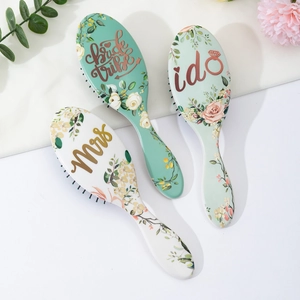 Detalle de cepillos de pelo con flores y letras de Bride Tribe y Mrs para bodas