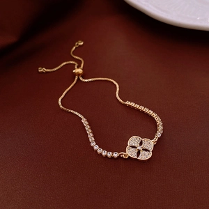 Detail of adjustable 18k gold plated bracelet featuring clover charm and pavé crystals