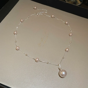 Close-up of irregular pearl pendant necklace on silver chain with small accent pearls