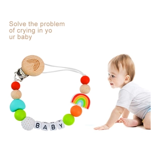 Detail of wooden beech rainbow pacifier clip with silicone beads and crochet yarn balls