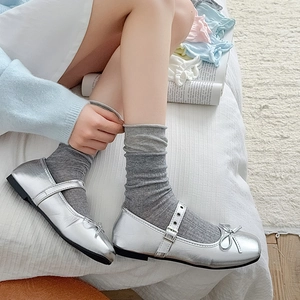 Silver Mary Jane shoes with bow detail paired with grey crew socks in a ballet style