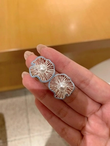 Close-up of a hollow flower earring with a white pearl center and blue petals