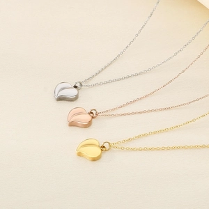 Three minimalist heart-shaped necklaces in silver, gold, and rose gold on beige background