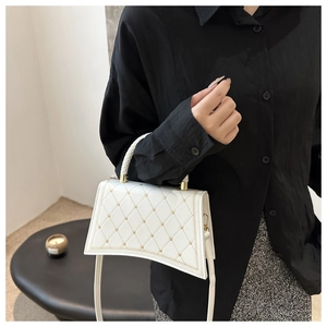 Detailed close-up of a white quilted tote bag featuring gold studs and woven top handles