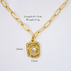 Detailed macro of golden paperclip chain necklace with textured rectangular pendant