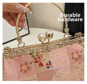 Detailed close-up of floral embroidery with pearl clasp and rhinestone trim on evening bag