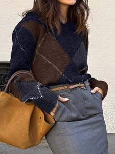 Pull en maille à losanges bleu foncé et marron porté avec un pantalon gris et un sac à main