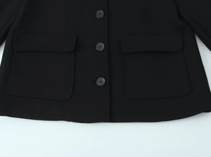 Detail of black wool blend coat showing two large flap pockets and round buttons