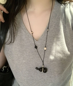 Detail of a vintage wax rope necklace featuring a wooden gourd pendant and pearl beads