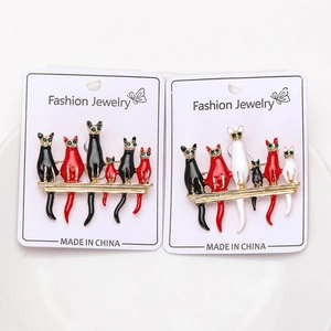 Detail view of multi-color enamel cat pins on gold branches with green rhinestone eyes