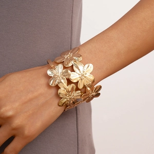 Close-up of golden layered flower cuff bracelet with textured petals on model wrist