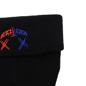 Dettaglio del ricamo rosso e blu su un berretto in maglia nera con trama fitta