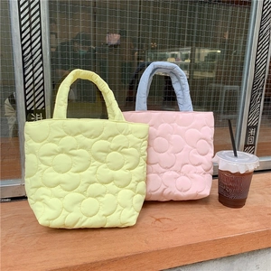 Close-up of quilted floral pattern on pastel yellow and pink macaron tote bags
