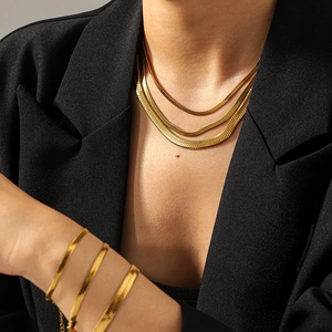 Detail of layered 18k gold plated stainless steel snake chain necklace on black suit