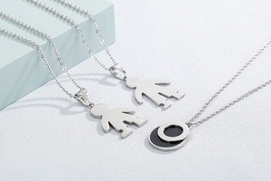 Detail view of silver boy silhouette pendants and round geometric necklace jewelry