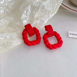 Détail macro de boucles d'oreilles cœur rouge mat avec anneau torsadé texturé