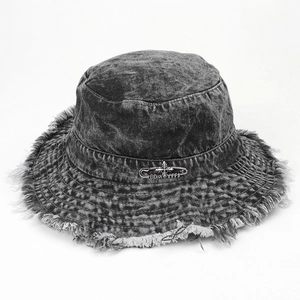 Detail of frayed edge denim bucket hat with silver cross pin and washed vintage texture