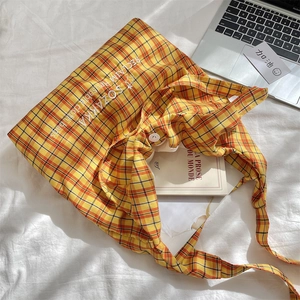 Detail of yellow checkered canvas tote bag with embroidery on a minimalist workspace