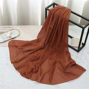 Detailed texture of caramel brown chiffon scarf draping over a black metal frame