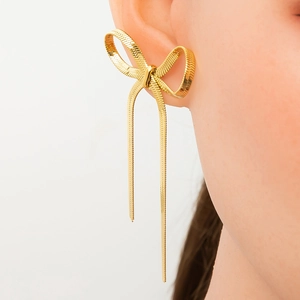 Detailed view of golden bow earrings with metal tassels worn by a female model