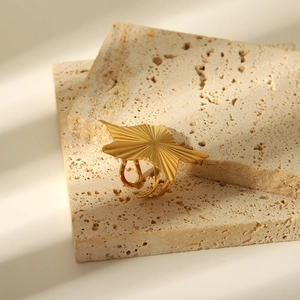 Macro detail of gold-plated sunburst textured ring on natural stone background