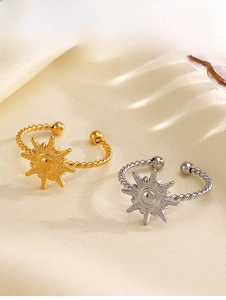 Detail of twisted band sunburst rings in gold and silver over yellow silk fabric