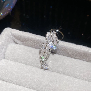 Macro shot of silver zircon feather ear cuff resting on a grey velvet jewelry box