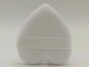 Detailed close-up of a white heart-shaped plush powder puff with a satin ribbon strap