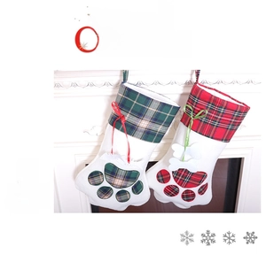 Close-up of pet paw Christmas stockings in red and green plaid on white fireplace
