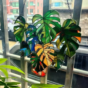 Stained glass monstera leaf window hanging with colorful patterns and metal chain