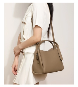 Detail of khaki pebbled leather bucket bag with round top handle and detachable strap