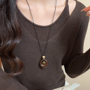 Close-up of vintage resin tiger eye oval pendant on a long dark sweater chain for women