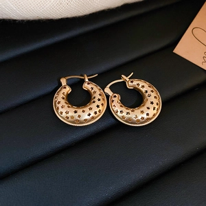 Detail of gold-plated hoop earrings featuring hollow star patterns and beaded textures