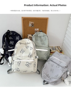 Detail of canvas butterfly print backpacks in black cream green and grey with plush charms