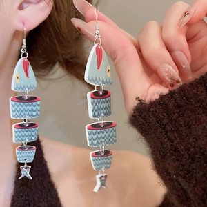 Detailed view of bohemian wood print fish pendant earrings with blue scales and red accents