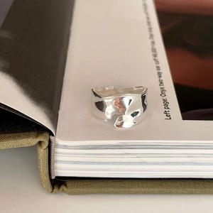 Macro detail of irregular wave liquid metal ring on white magazine pages