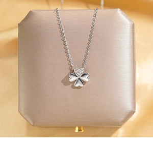 Detailed view of silver four-leaf clover pendant with pavé heart on champagne velvet